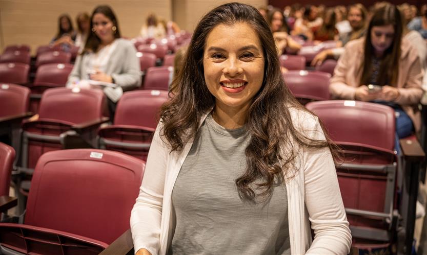A woman smiles while sitting in an auditorium seat